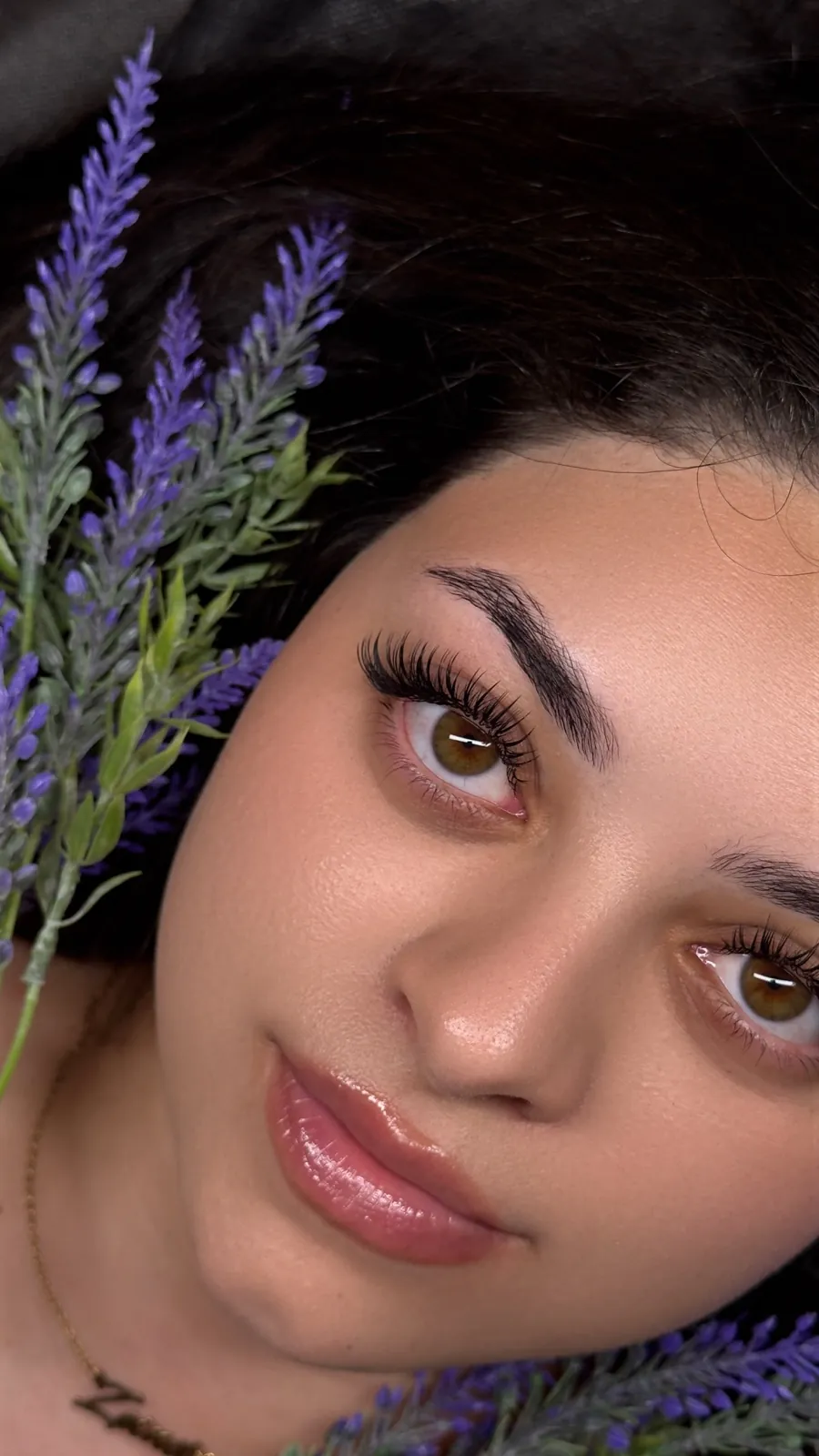 Close-up of a Bond Beauty client with flawless lash extensions and brows, framed by lavender
